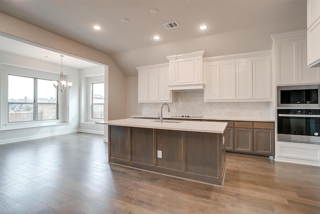 kitchen featuring dark wood-type flooring, white cabinetry, a kitchen island with sink, and black appliances