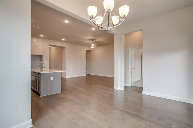 kitchen featuring ceiling fan with notable chandelier, white cabinets, dark wood-type flooring, sink, and hanging light fixtures