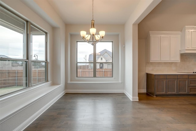 unfurnished dining area with dark hardwood / wood-style floors, a wealth of natural light, and a chandelier