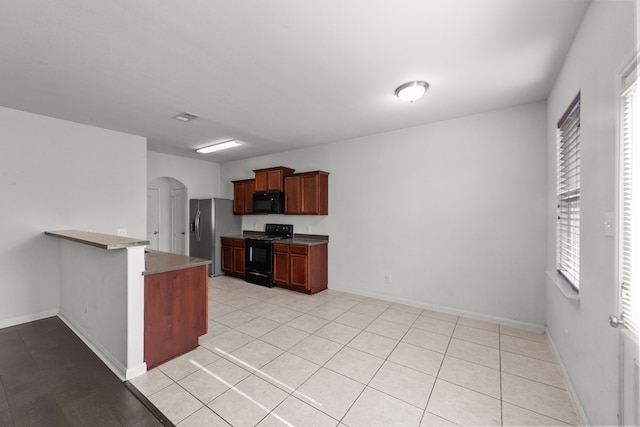 kitchen featuring kitchen peninsula, light tile patterned floors, and black appliances