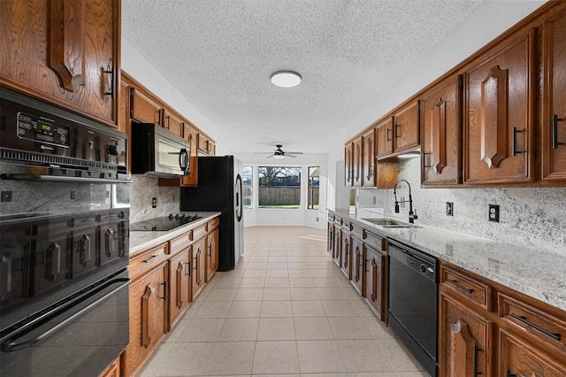 kitchen with sink, light stone counters, tasteful backsplash, light tile patterned floors, and black appliances