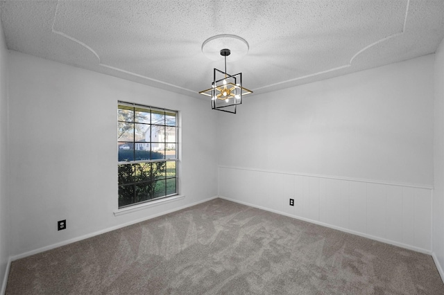 carpeted spare room featuring a textured ceiling and a chandelier