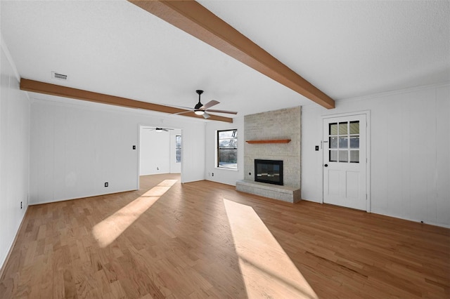 unfurnished living room featuring ceiling fan, light hardwood / wood-style flooring, a large fireplace, and beamed ceiling