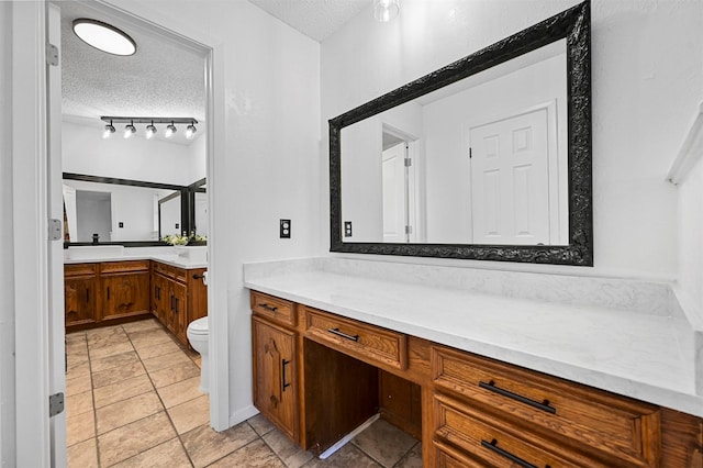 bathroom with vanity, track lighting, toilet, and a textured ceiling