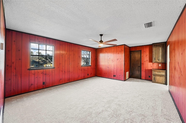 unfurnished bedroom featuring ceiling fan, light colored carpet, and a textured ceiling