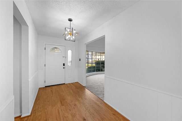 entryway featuring a chandelier, a textured ceiling, and light wood-type flooring