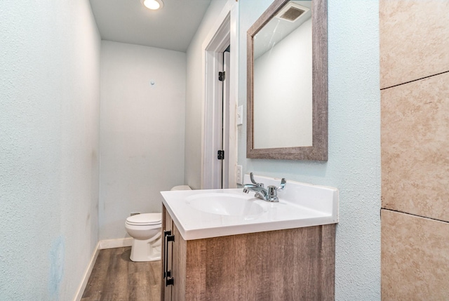 bathroom featuring wood-type flooring, toilet, and vanity