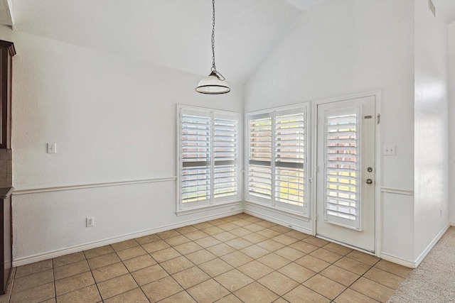 unfurnished dining area featuring light tile patterned floors and vaulted ceiling