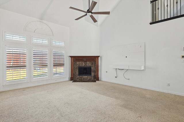 unfurnished living room with ceiling fan, a fireplace, high vaulted ceiling, and light carpet