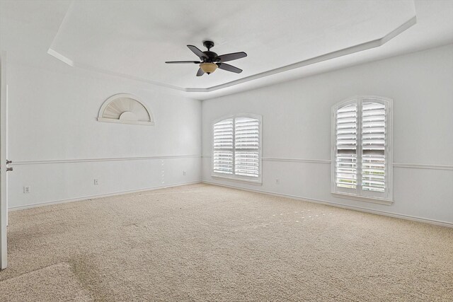 carpeted spare room featuring ceiling fan and a raised ceiling