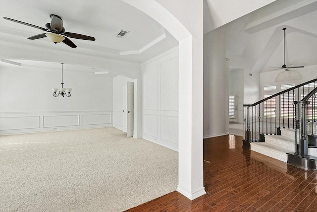 interior space featuring dark colored carpet, ceiling fan with notable chandelier, and lofted ceiling