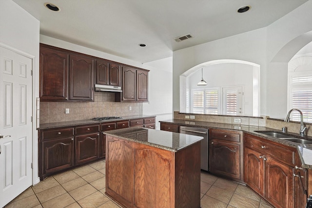 kitchen featuring a center island, sink, decorative backsplash, light tile patterned floors, and appliances with stainless steel finishes