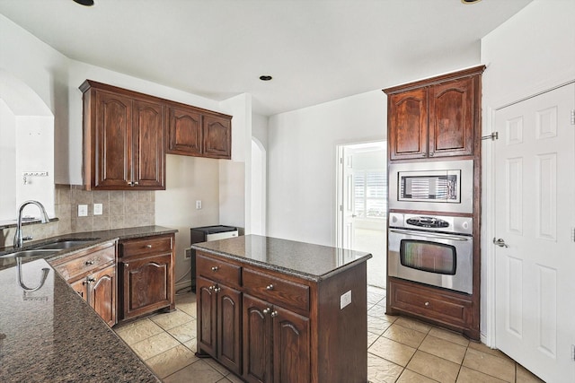 kitchen with backsplash, light tile patterned flooring, sink, and appliances with stainless steel finishes