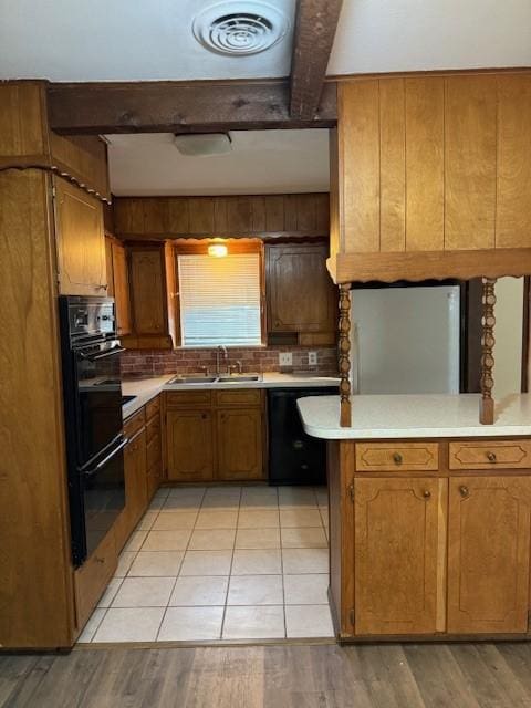 kitchen featuring beam ceiling, sink, kitchen peninsula, decorative backsplash, and black appliances