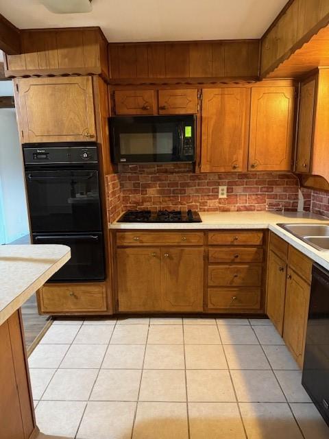 kitchen with light tile patterned floors, sink, and black appliances