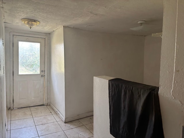 doorway to outside with a textured ceiling and light tile patterned floors