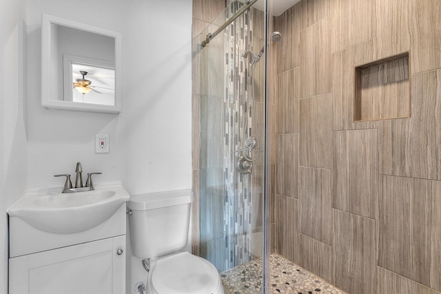 bathroom featuring a shower with door, vanity, and toilet