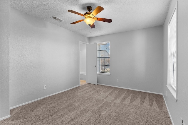 unfurnished room with carpet flooring, ceiling fan, and a healthy amount of sunlight