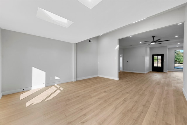 unfurnished living room with light wood-type flooring, a skylight, and ceiling fan