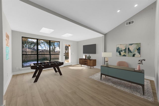 rec room featuring lofted ceiling with skylight and light hardwood / wood-style flooring