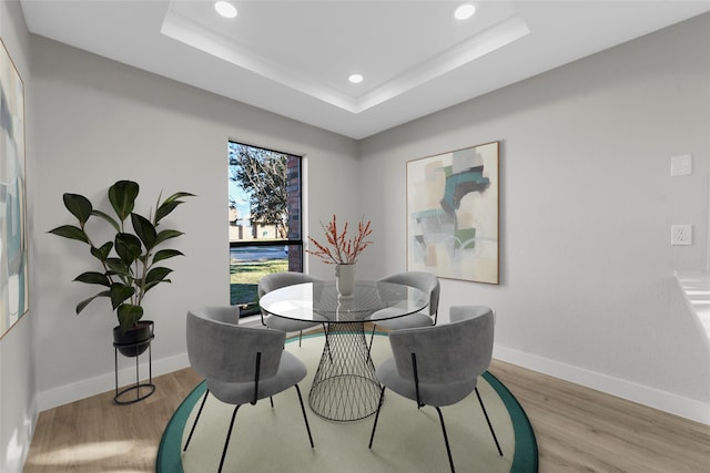 dining area featuring a raised ceiling and light hardwood / wood-style floors