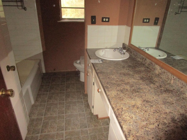 bathroom featuring vanity, a tub to relax in, and toilet