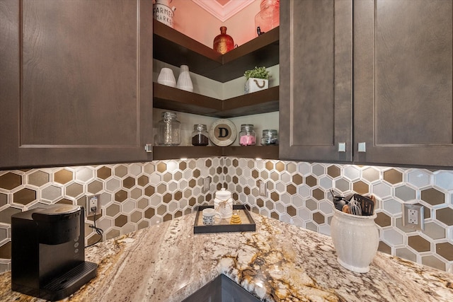 kitchen featuring light stone counters, dark brown cabinetry, decorative backsplash, and open shelves