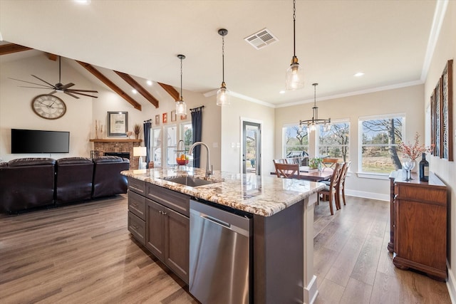 kitchen featuring light stone counters, a sink, visible vents, stainless steel dishwasher, and light wood finished floors