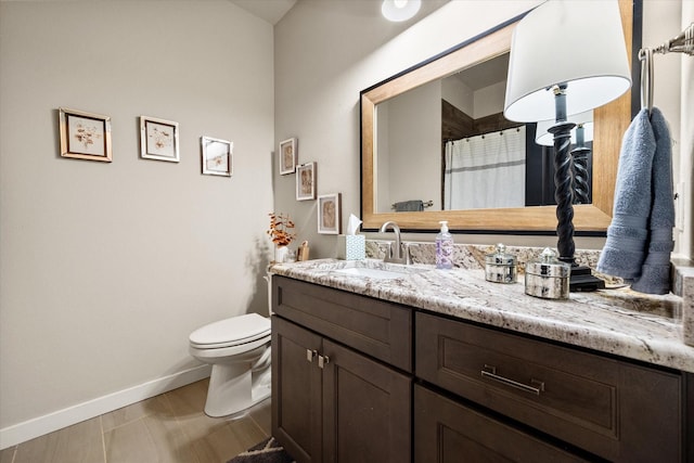 full bathroom featuring toilet, baseboards, and vanity