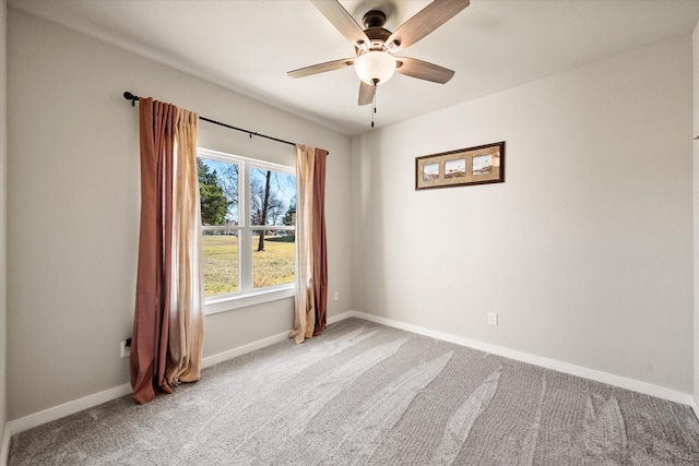 spare room featuring a ceiling fan, light colored carpet, and baseboards