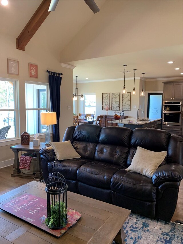 living area featuring lofted ceiling with beams, recessed lighting, wood finished floors, and crown molding