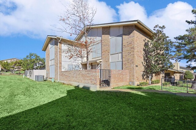 back of property with central AC unit and a yard