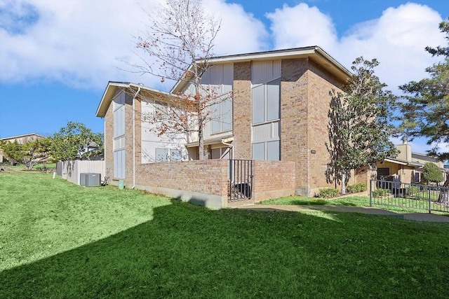 rear view of property with central AC and a lawn