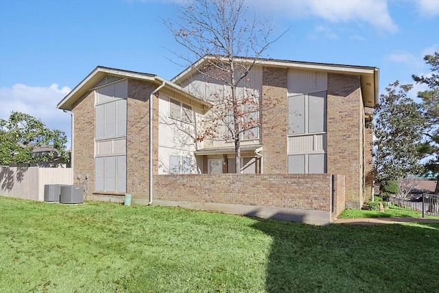 rear view of house featuring central AC and a lawn