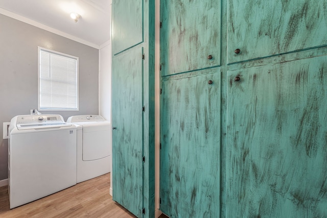 clothes washing area featuring cabinets, ornamental molding, light hardwood / wood-style floors, and washing machine and dryer