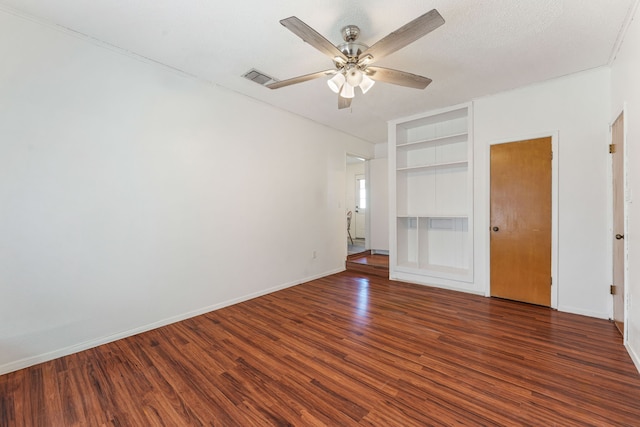 spare room with dark hardwood / wood-style flooring, a textured ceiling, built in features, and ceiling fan