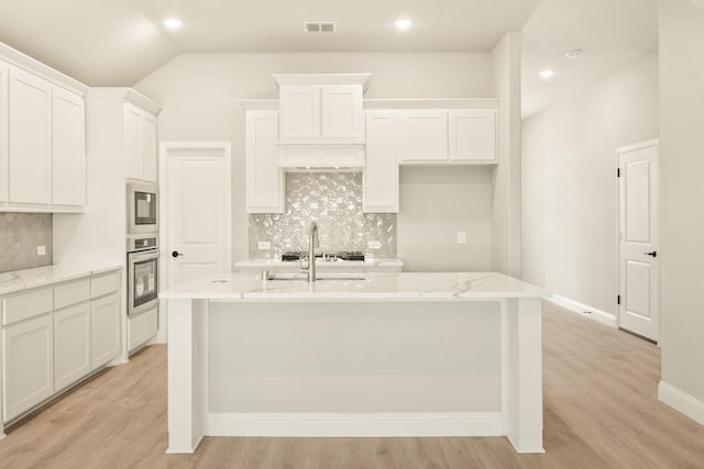 kitchen featuring light wood-style floors, a kitchen island with sink, visible vents, and stainless steel oven