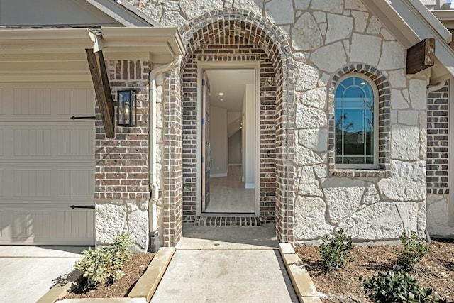 view of exterior entry featuring a garage and brick siding