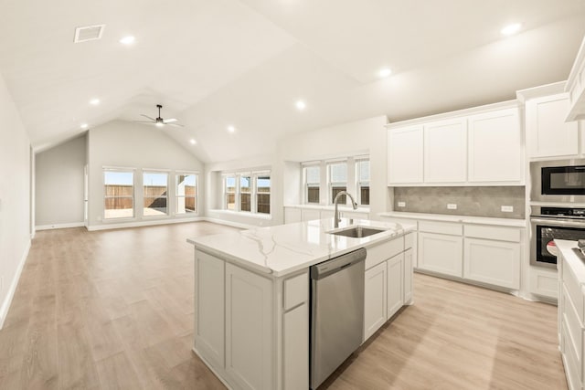 kitchen with stainless steel appliances, visible vents, a kitchen island with sink, vaulted ceiling, and a sink