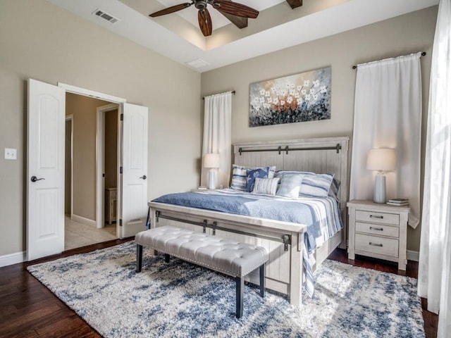 bedroom with hardwood / wood-style flooring, a raised ceiling, and ceiling fan