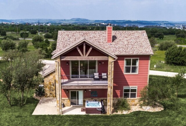 back of property with a fire pit, a patio area, a yard, and a balcony