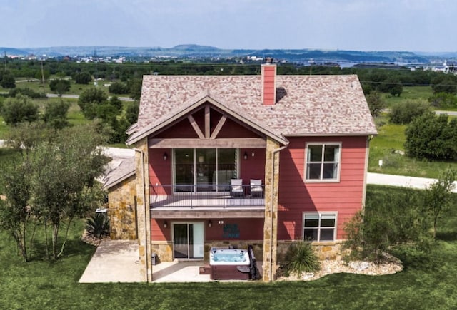 back of property with a balcony, a hot tub, and a patio area