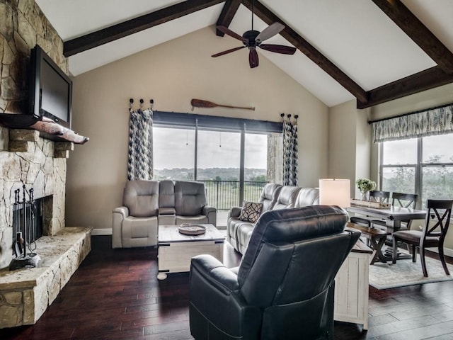 living room featuring beam ceiling, a stone fireplace, dark wood-type flooring, and plenty of natural light