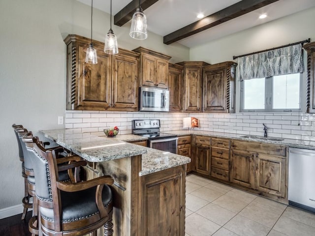 kitchen featuring appliances with stainless steel finishes, a breakfast bar, decorative light fixtures, sink, and kitchen peninsula