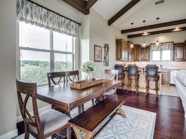 dining area with dark hardwood / wood-style flooring, high vaulted ceiling, and beam ceiling