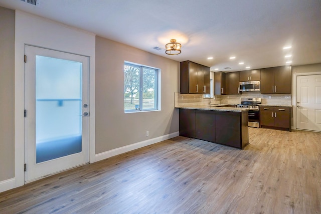 kitchen featuring kitchen peninsula, dark brown cabinets, stainless steel appliances, and sink