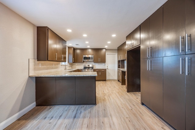 kitchen featuring sink, stainless steel appliances, light hardwood / wood-style flooring, kitchen peninsula, and decorative backsplash