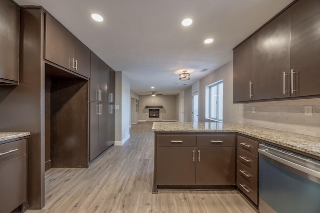 kitchen featuring kitchen peninsula, light stone countertops, and stainless steel dishwasher