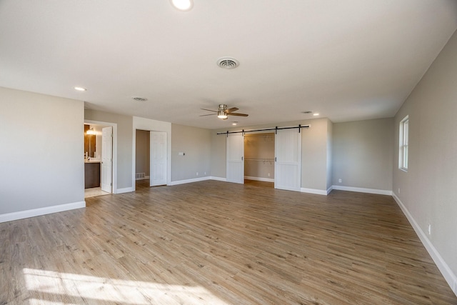 unfurnished living room featuring a barn door and light hardwood / wood-style flooring