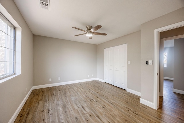 unfurnished bedroom with ceiling fan, a closet, and light wood-type flooring